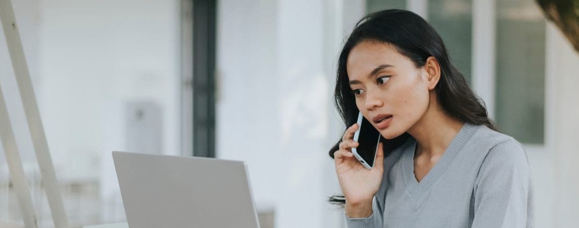 woman on phone call looking at laptop screen